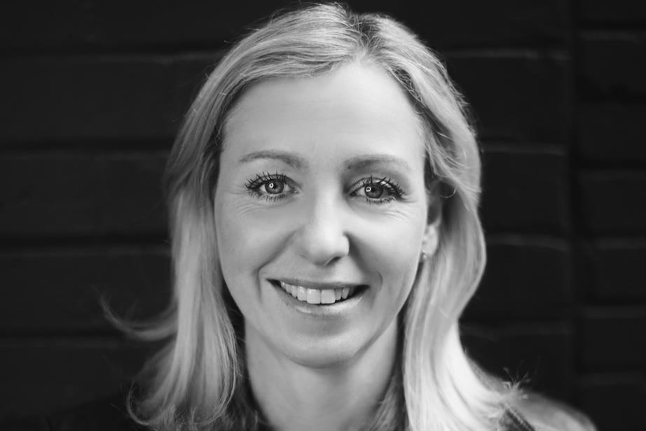 A black and white portrait of Claire Hollands, who is smiling into the camera