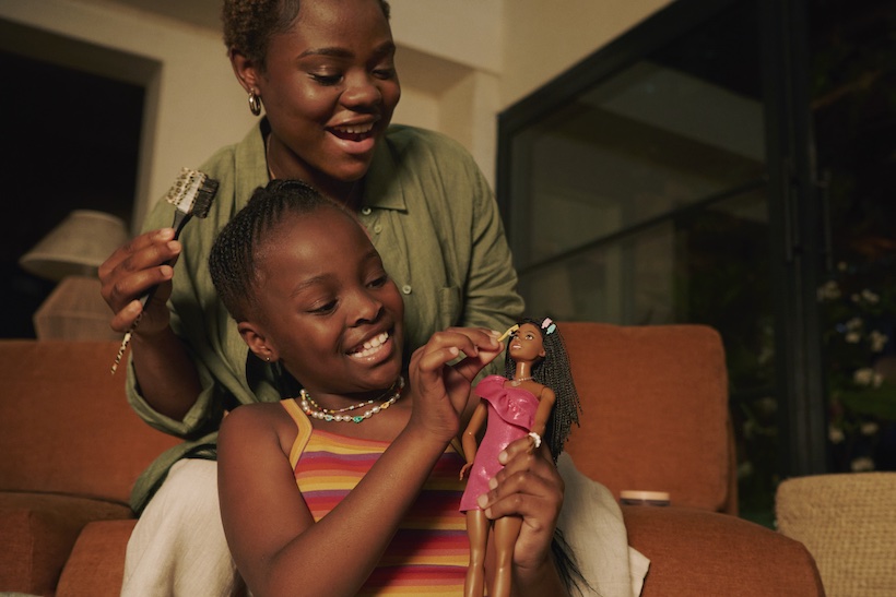 Girl and her mother play with a Barbie doll