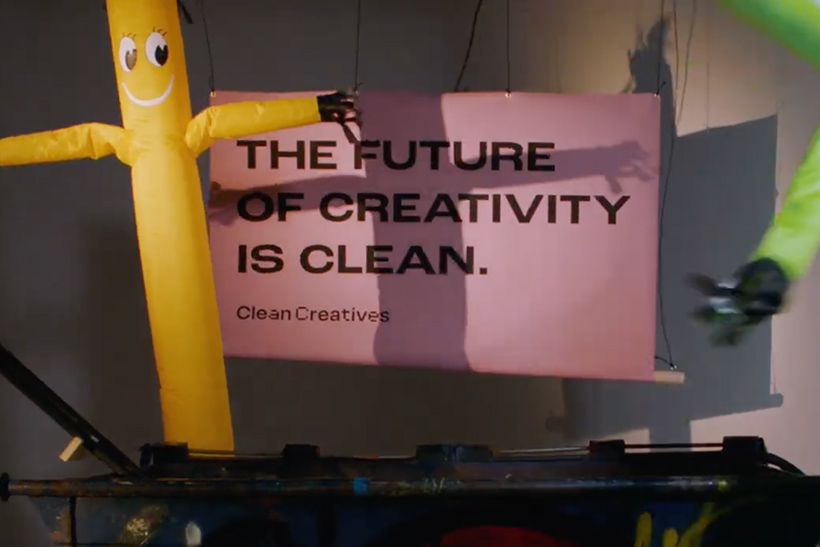 Inflatable tube dancers in front of sign reading "The future of creativity is clean"