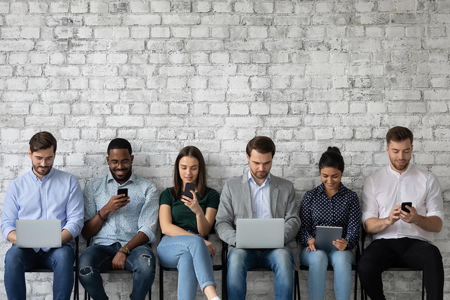 A group of six young people look using digital media devices.