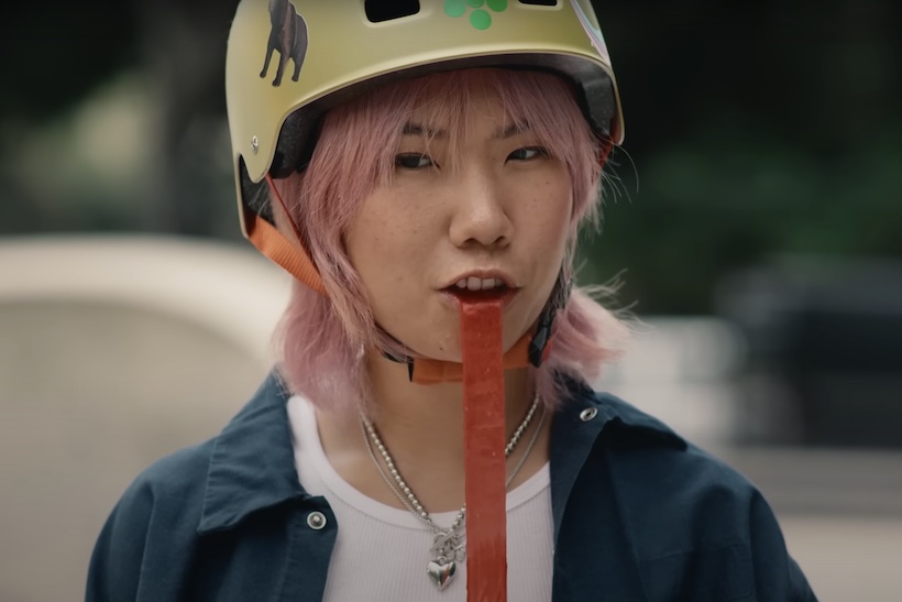 Person with pink hair eating Fruit by the Foot