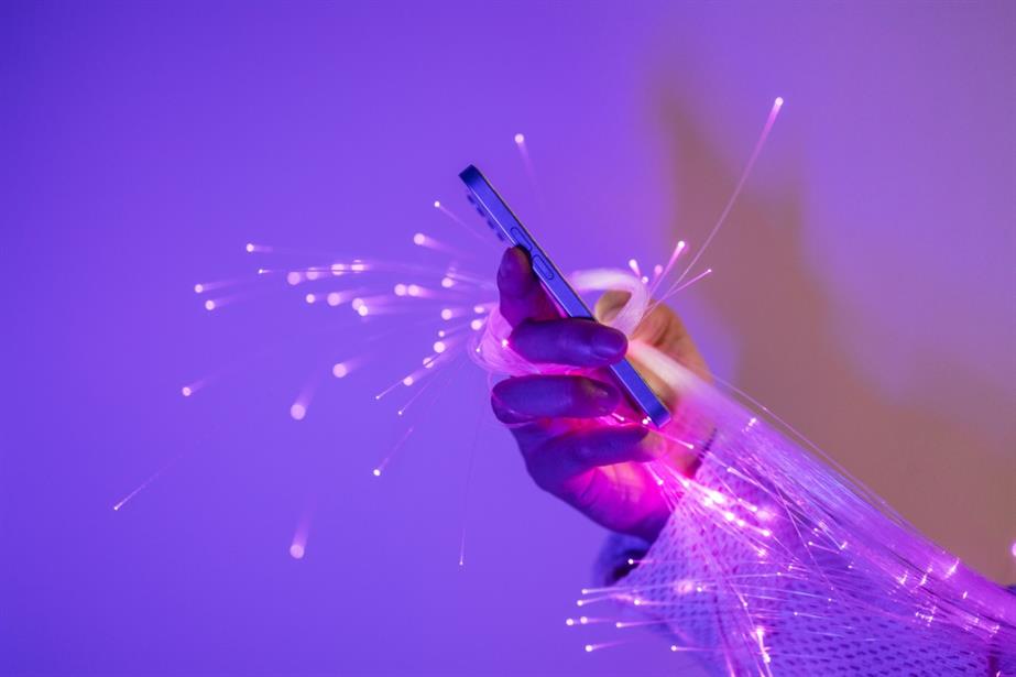 A hand holding a smartphone with sparks of light emerging from it