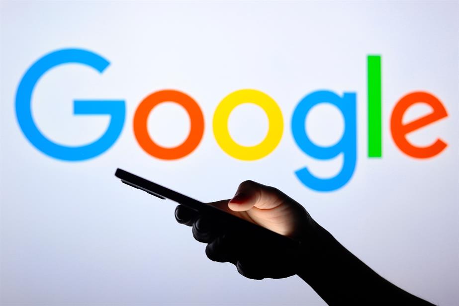 The Google logo with someone scrolling through their phone in front of the screen.