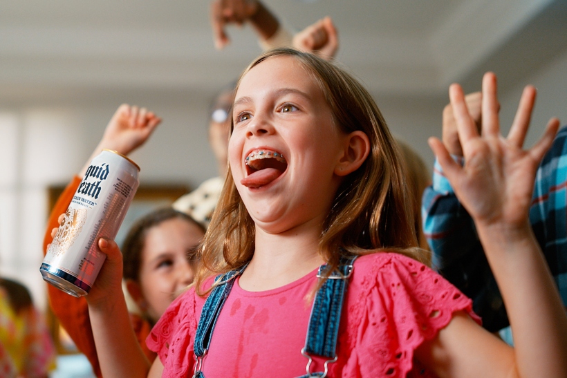 Young girl drinking from Liquid Death water can at a kids' party 