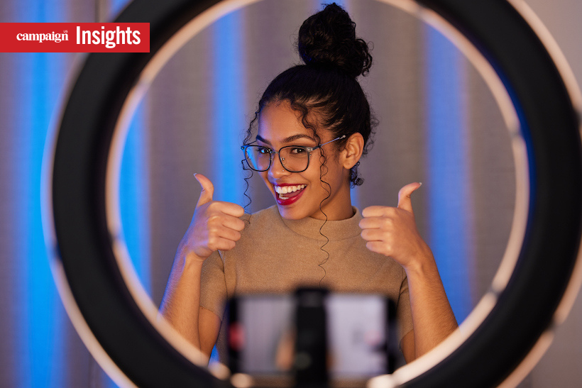 young woman showing a thumbs up while using a phone to film at home