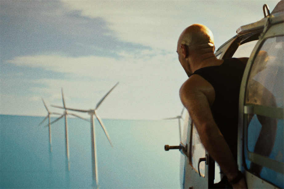 a man in a helicopter looking at wind turbines